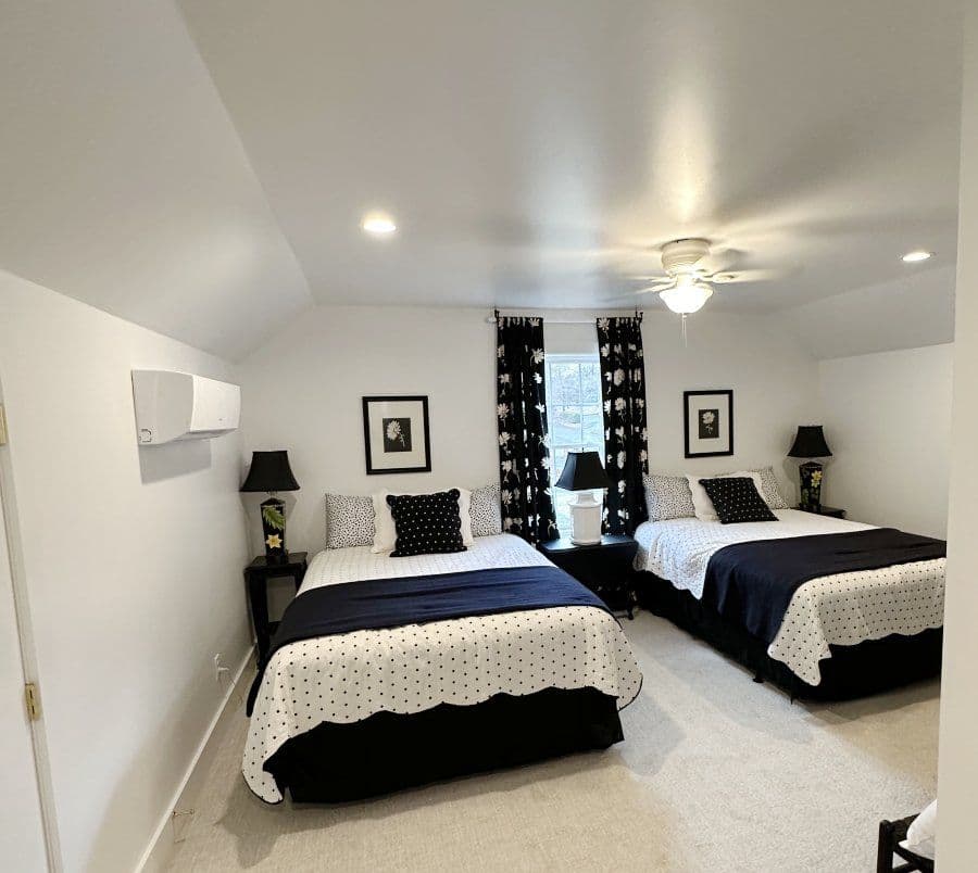 Cozy bedroom with two double beds, floral curtains, and modern decor. Ideal for relaxation.