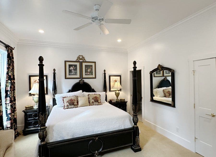 Elegant bedroom featuring a four-poster bed, decorative lamps, and a stylish mirror.