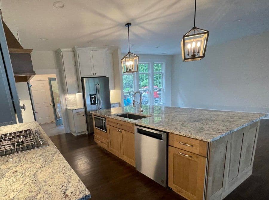 Modern kitchen with granite island, stainless steel appliances, and pendant lighting.