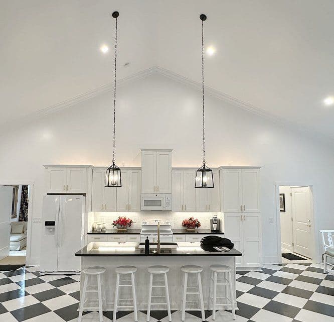 Modern kitchen with black and white checkered floor, pendant lights, and white cabinetry.