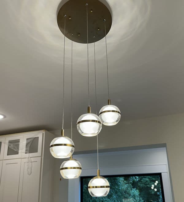 Modern pendant lights with glass globes hanging from a ceiling fixture in a kitchen.