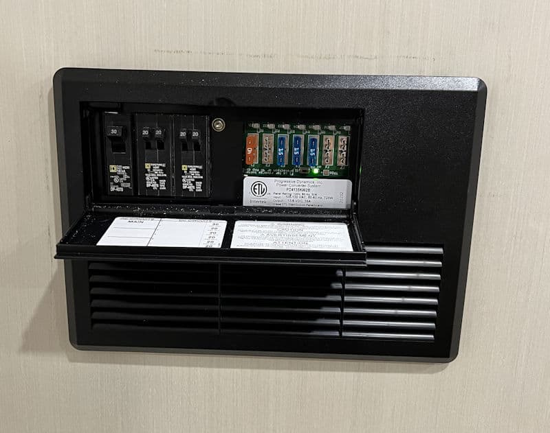 Circuit breaker panel with fuses and labels, mounted on a wall. Safe power management.